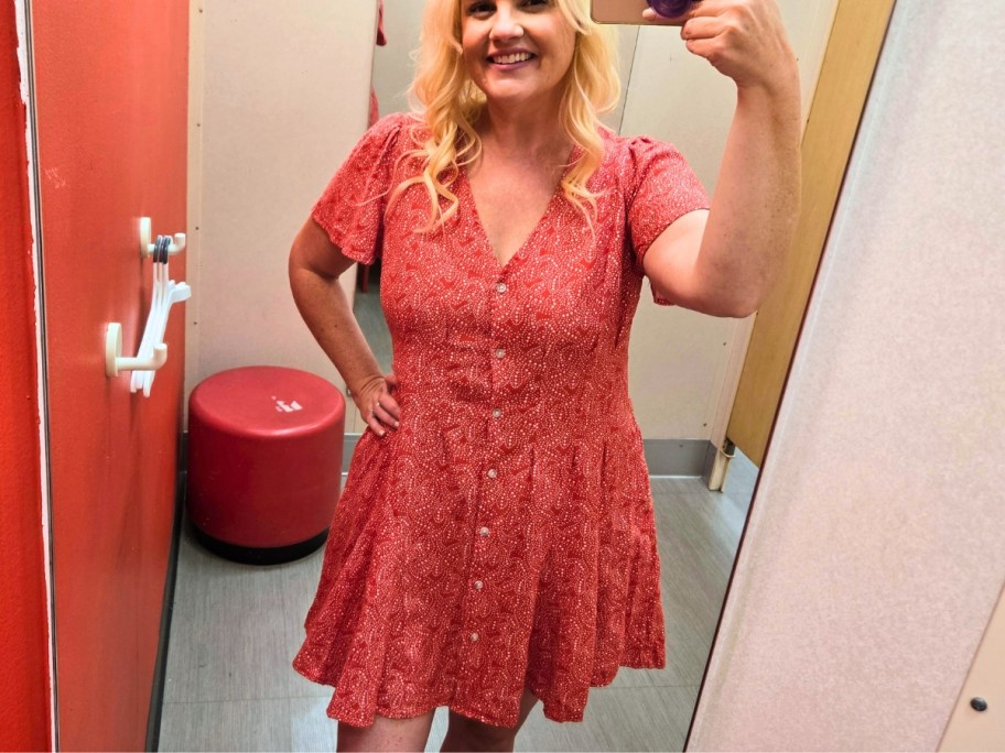 woman taking a selfie in a dressing room mirror wearing a red and white v neck flutter dress