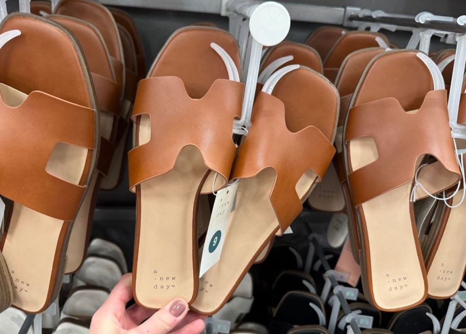 a womans hand holding the heel of a slide sandal