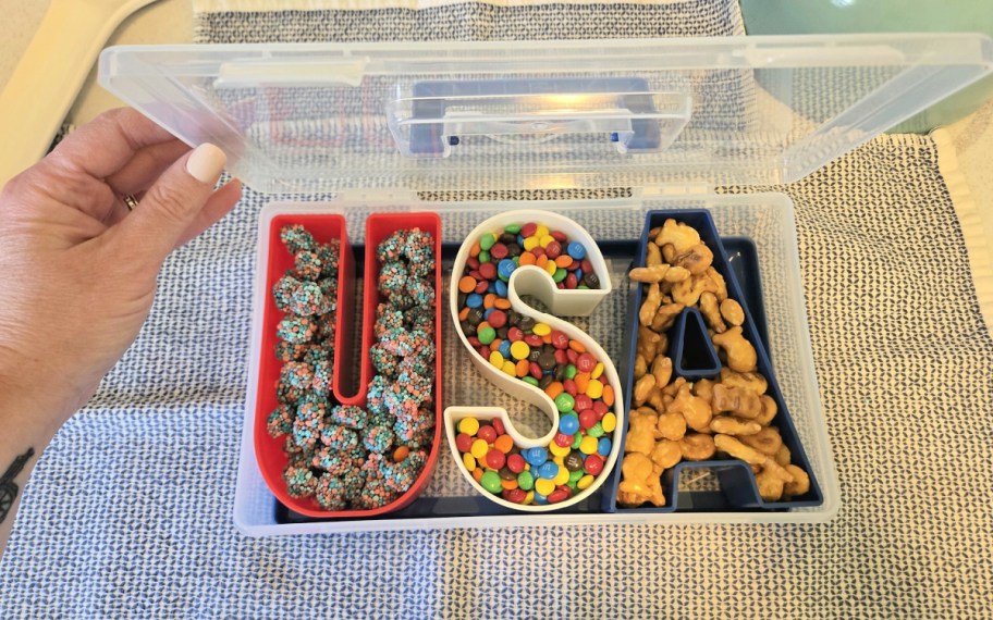 person lifting the lid on a usa snackle box full of candy