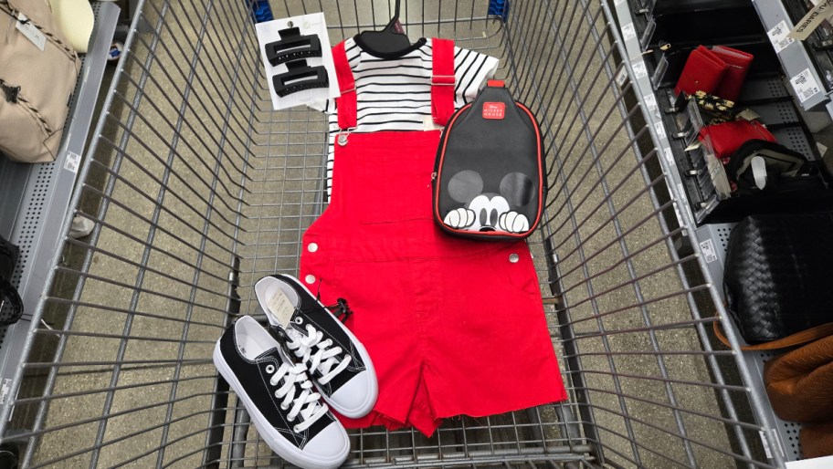 red shortalls, a striped shirt, and accessories in a Walmart shopping cart