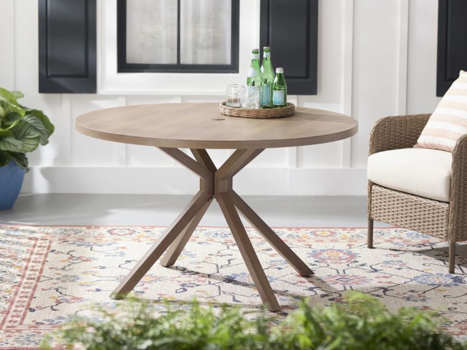 The Mainstays Chelsea Outdoor Dining Table on a patio next to a chair