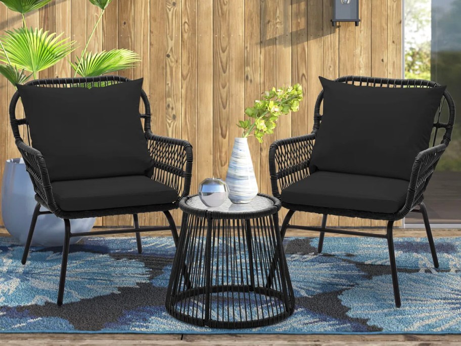 two black chairs and table on patio with decor