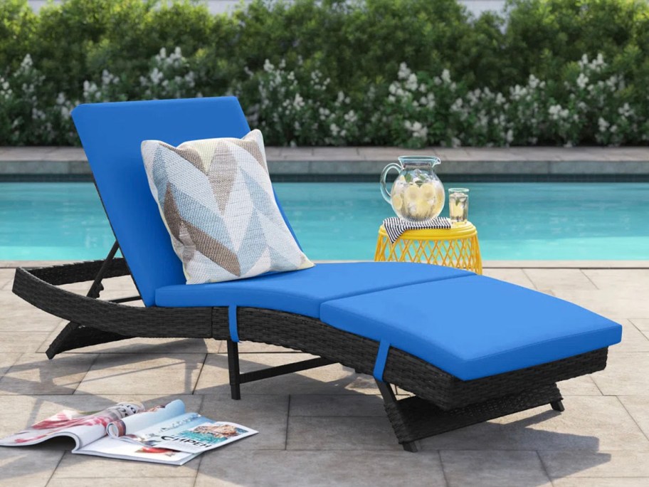 black lounge chair with blue cushion next to pool 