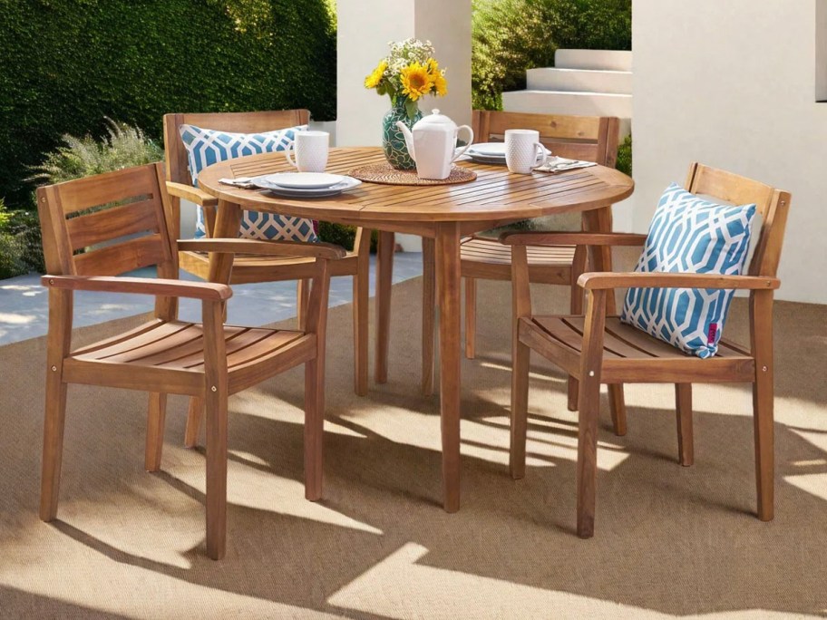 table and 4 teak chairs with pillows on patio 