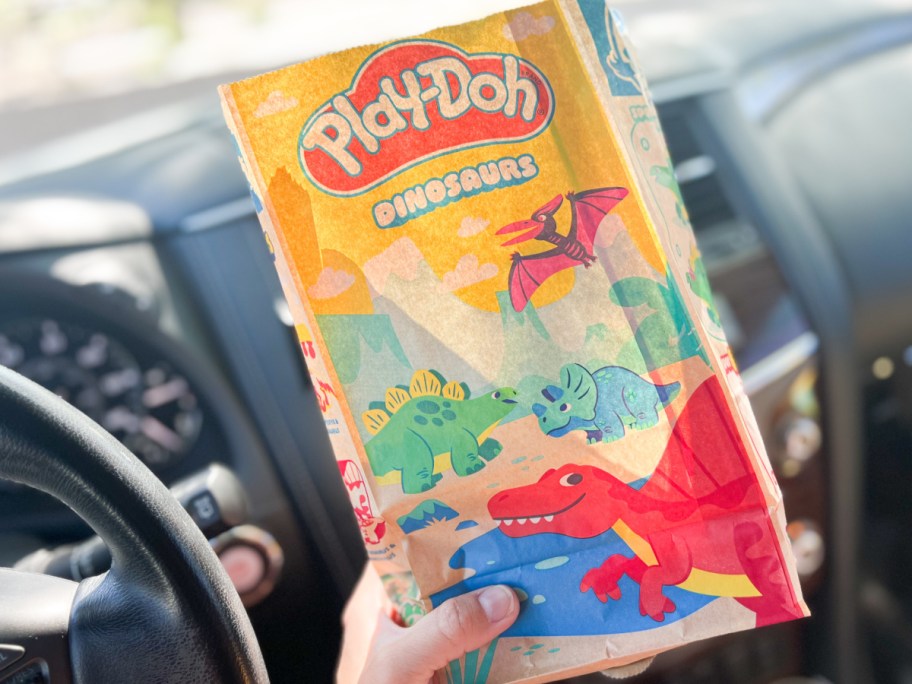 hand holding wendys kids meal bag in car
