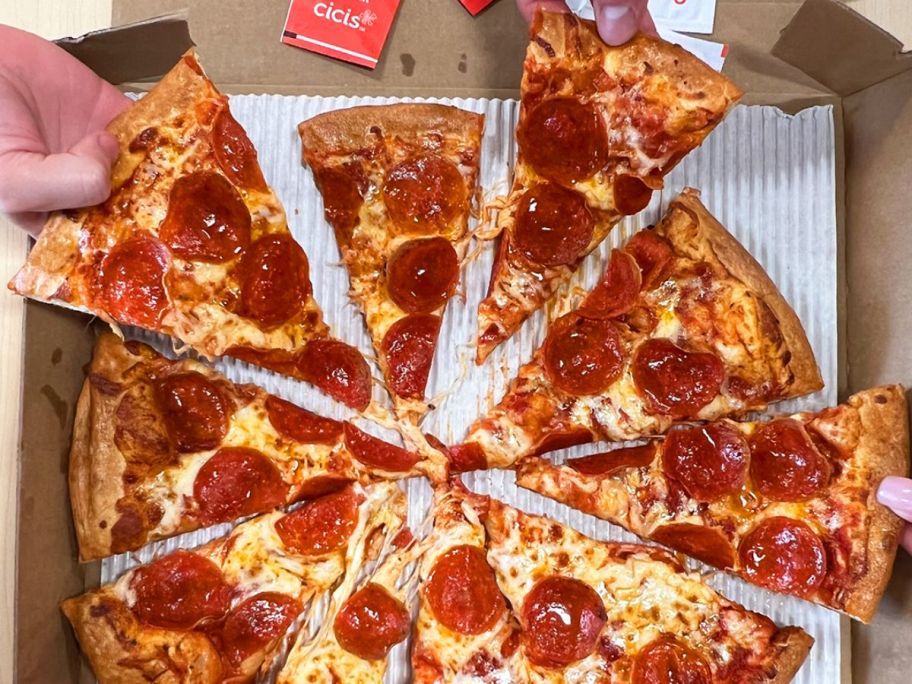 a pepperoni pizza with several hands grabbing a piece