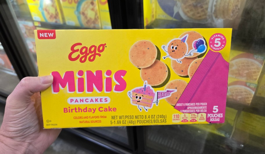 hand holding birthday cake mini pancakes box in front of freezer
