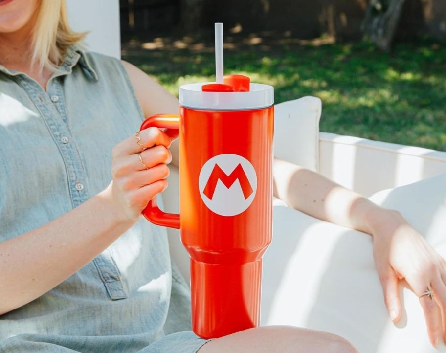 a womans hand holding a red tumbler