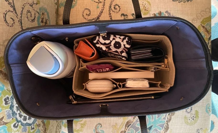 an open handbag showing a purse insert and water bottle