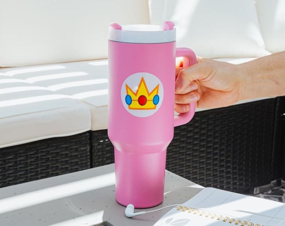 a womans hand holding a pink tumbler