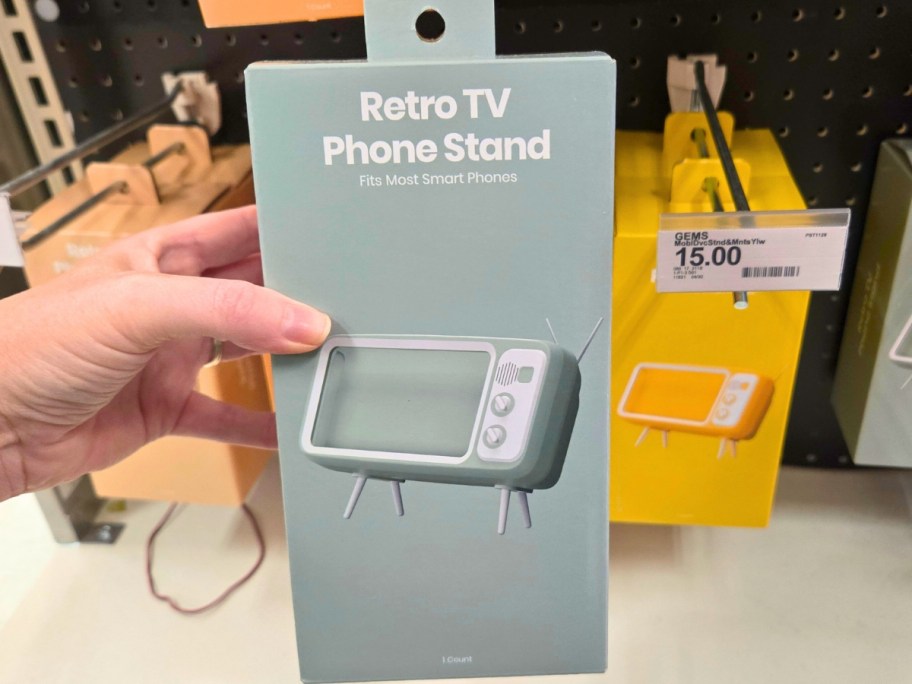 hand holding a box with a retro tv phone stand in it, more on a store shelf behind it
