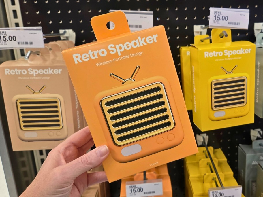 hand holding a box with mini retro speaker, more on a store shelf behind it